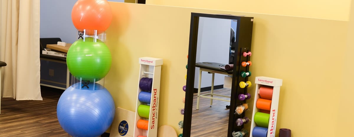 Stacked exercise balls, Sanctband resistance bands and a mirror in the clinic's exercise area